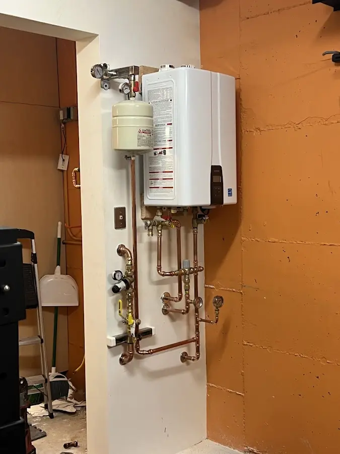 Plumbing technician inspecting water heater connections in Libby